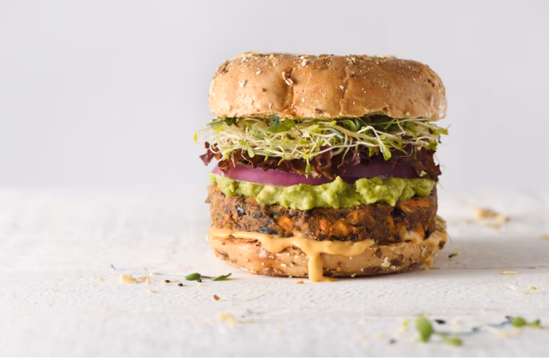 Burger vegetale a base di fagioli con guacamole, germogli e cipolla rossa